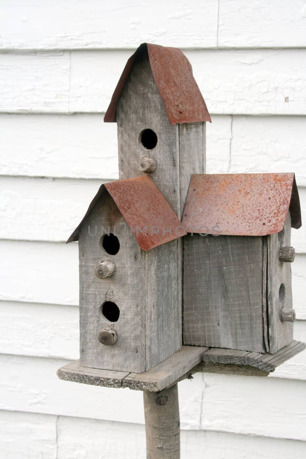 a rustic birdhouse, with rusted metal roof, available for three families