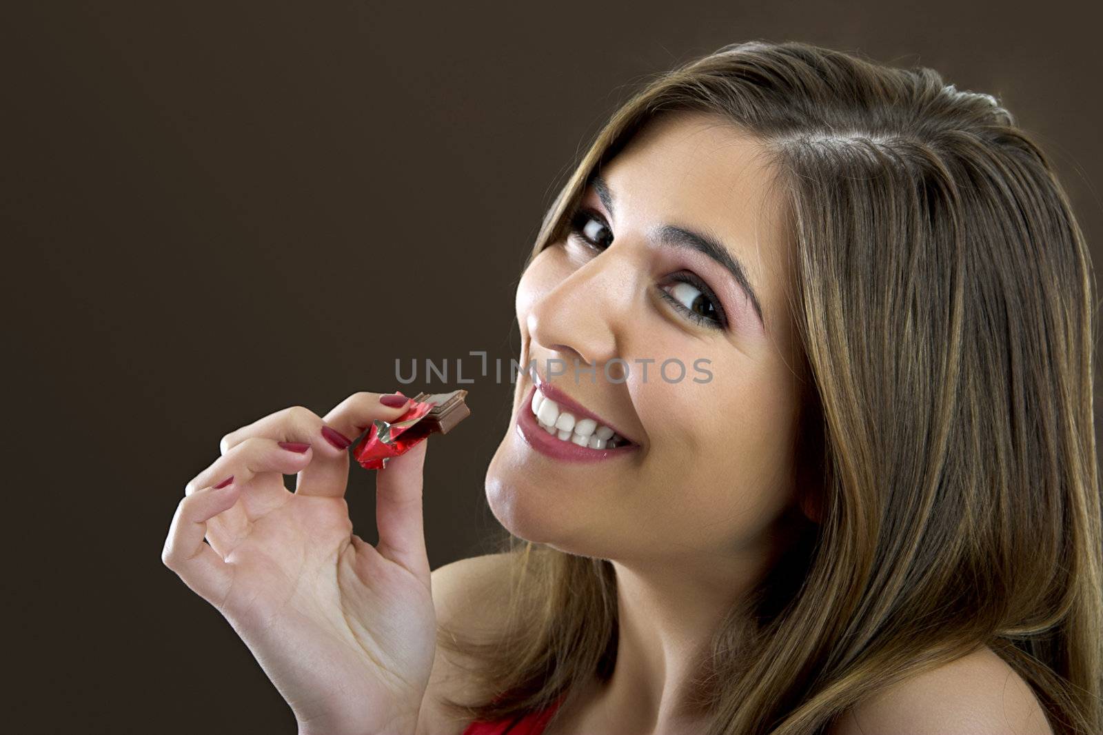 A beautiful happy woman satisfying a chocolate candy