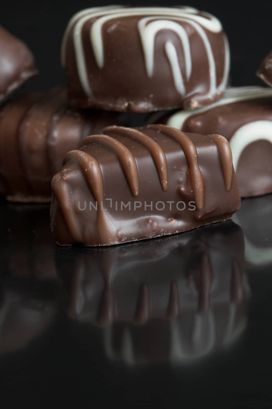 Delicious chocolates on black background with reflection