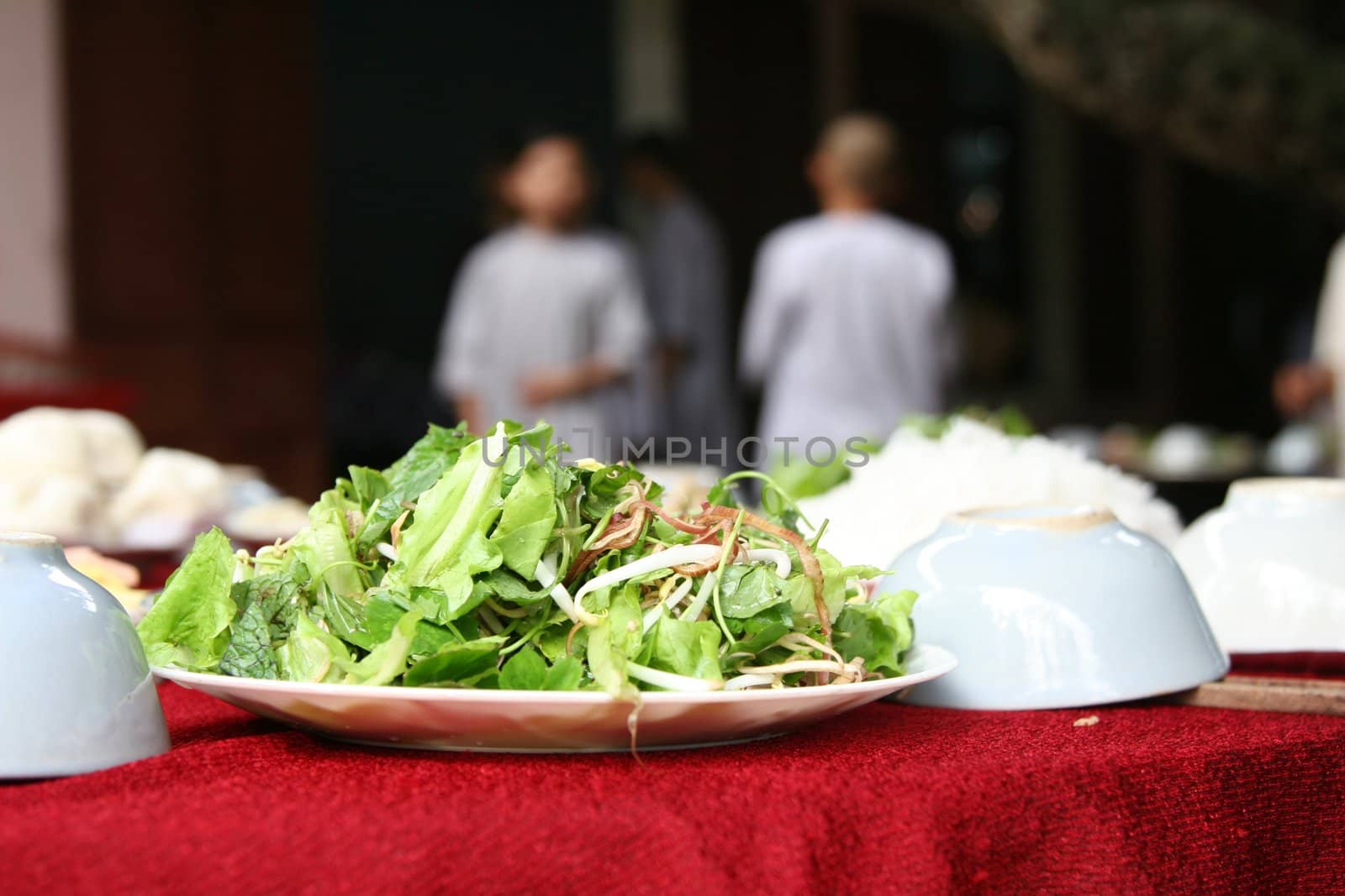 Fresh green salad served on a table with people in the background