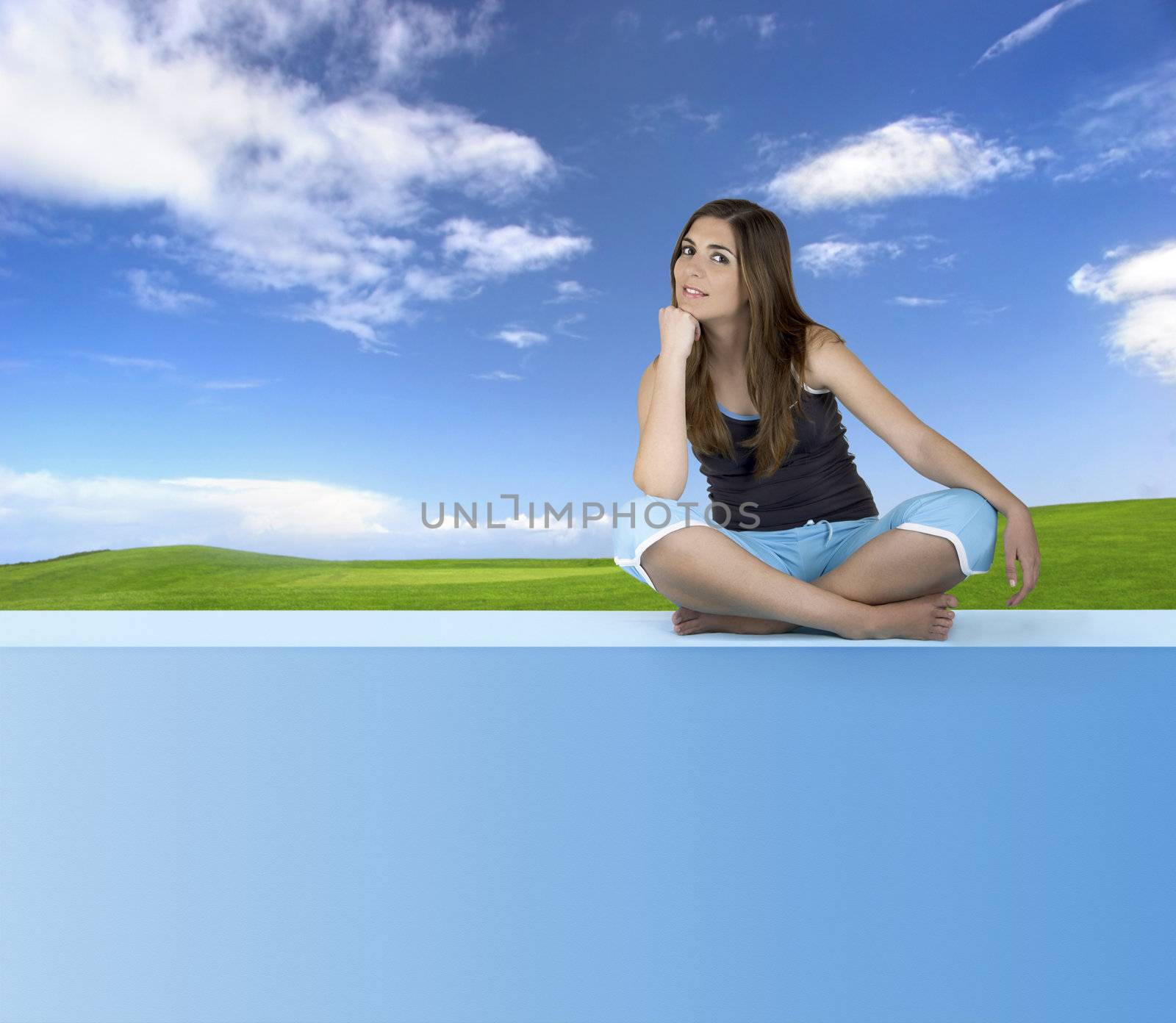 Beautiful Athletic woman seated and relaxing on a blue wall