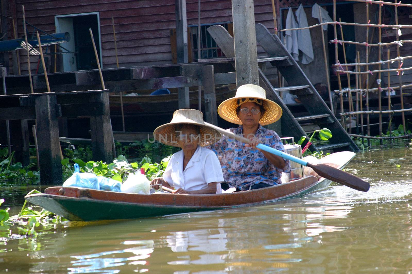 Two women having just come back from the market with their boat filled with fresh vegetables