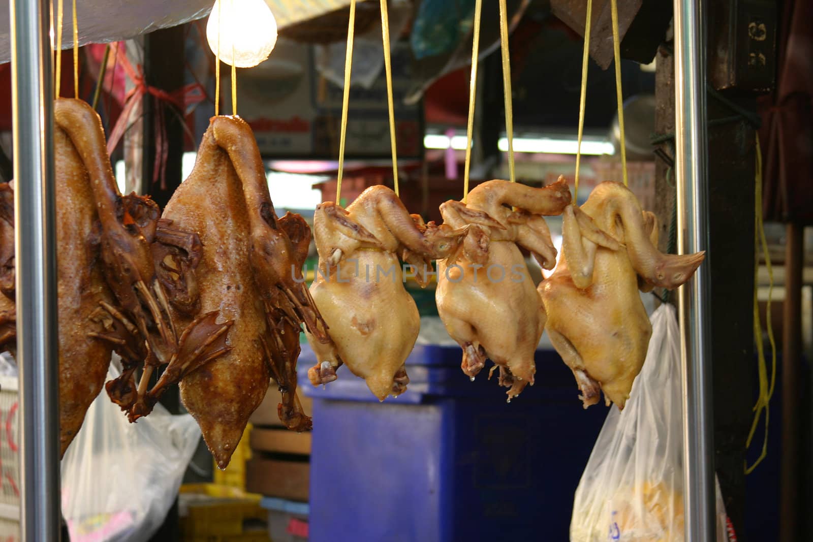 Freshly grilled chicken hanging in a stall in Bangkok waiting to be sold