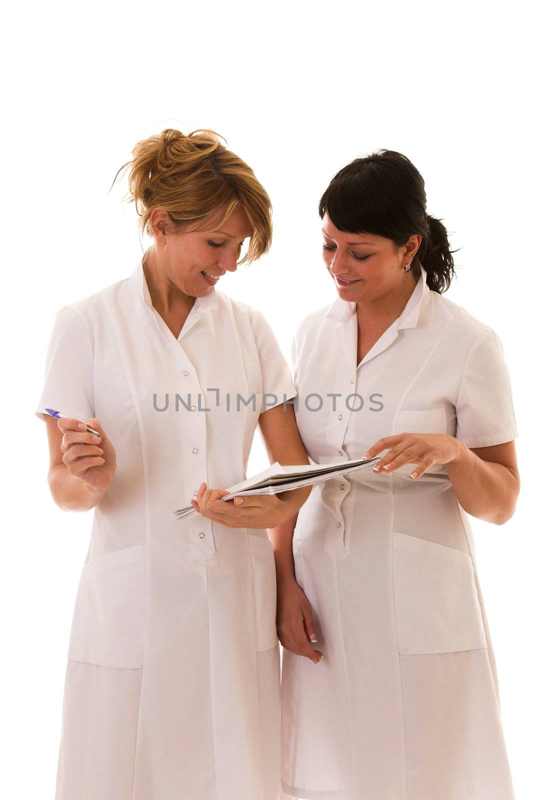 Two nurses standing next to each other compairing notes