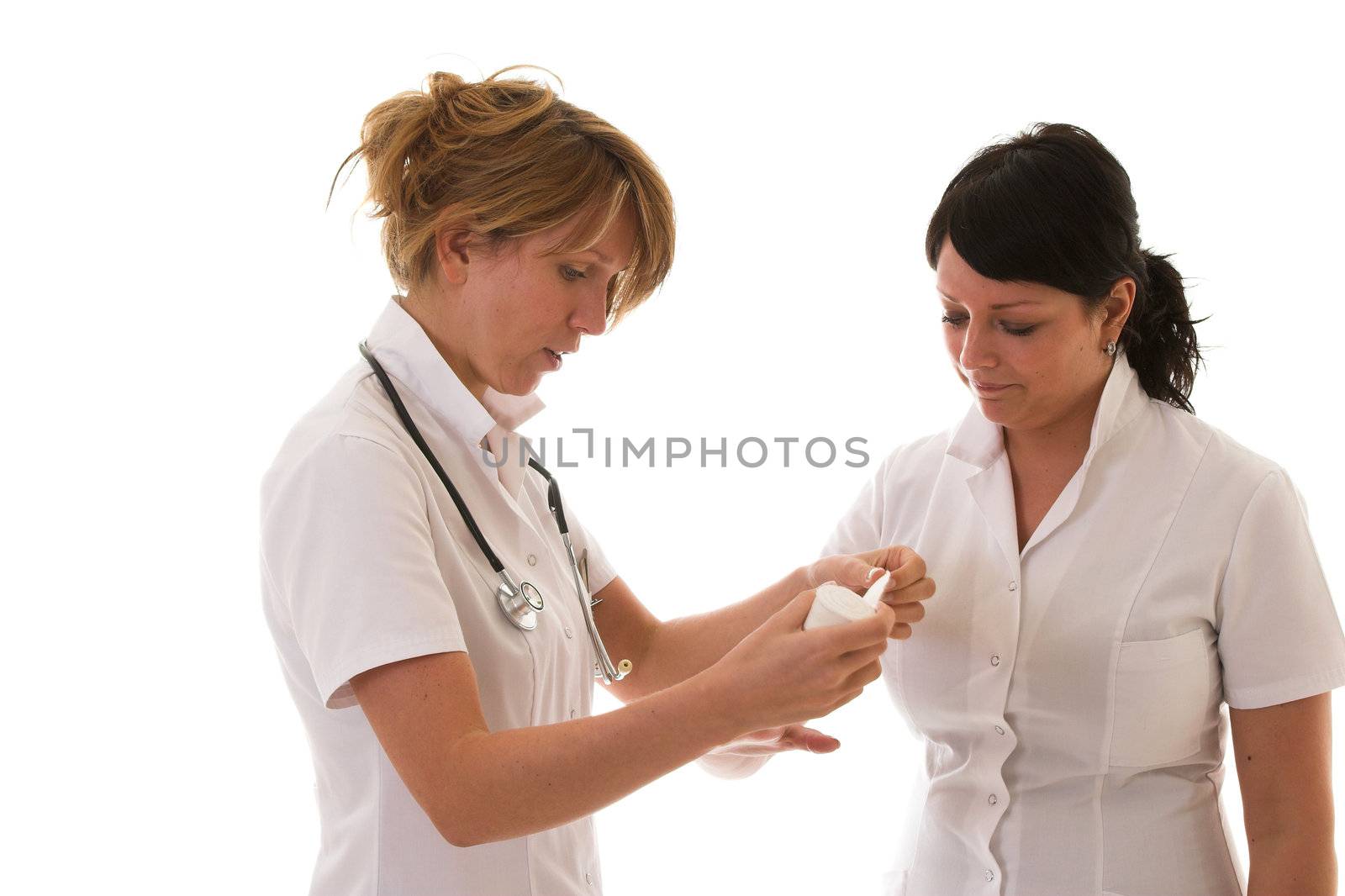 Two nurses standing next to eachother while one is going to learn the other how to put on a tape around a hand