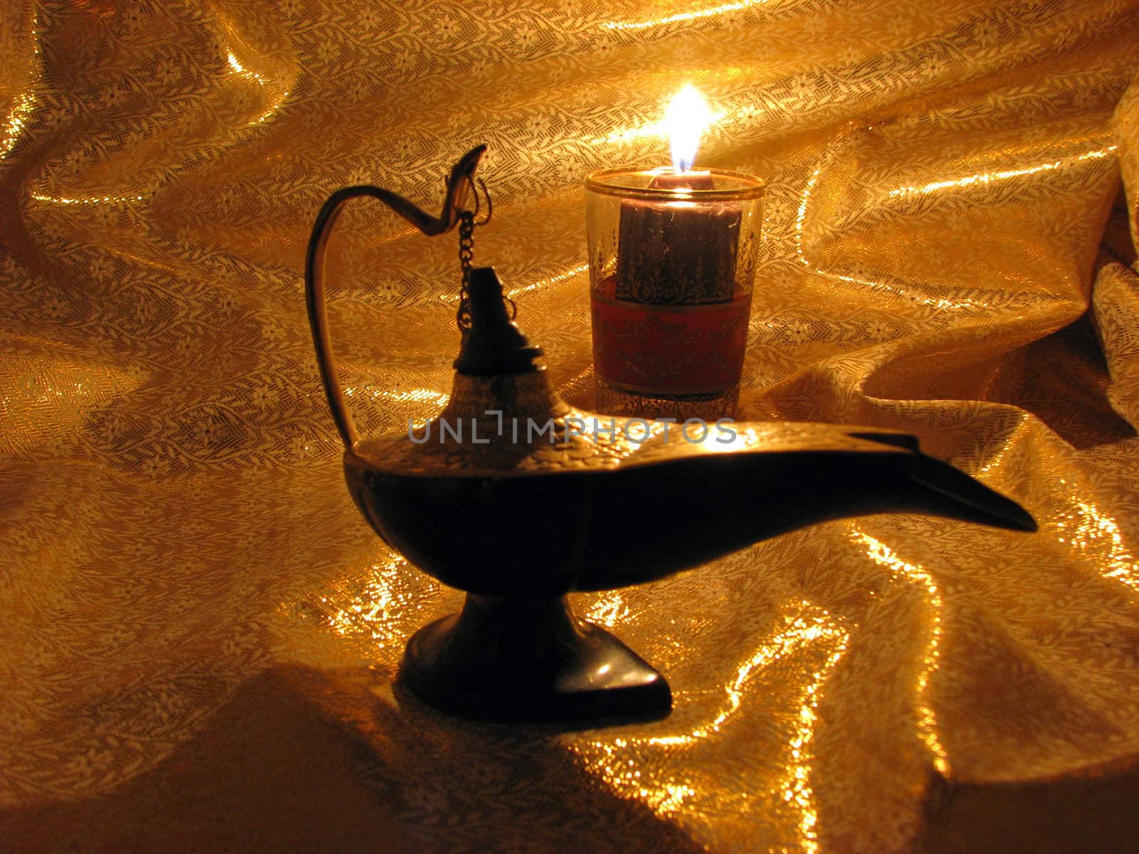 An India Aladdin's Lamp on a dark gold background with candlelight.