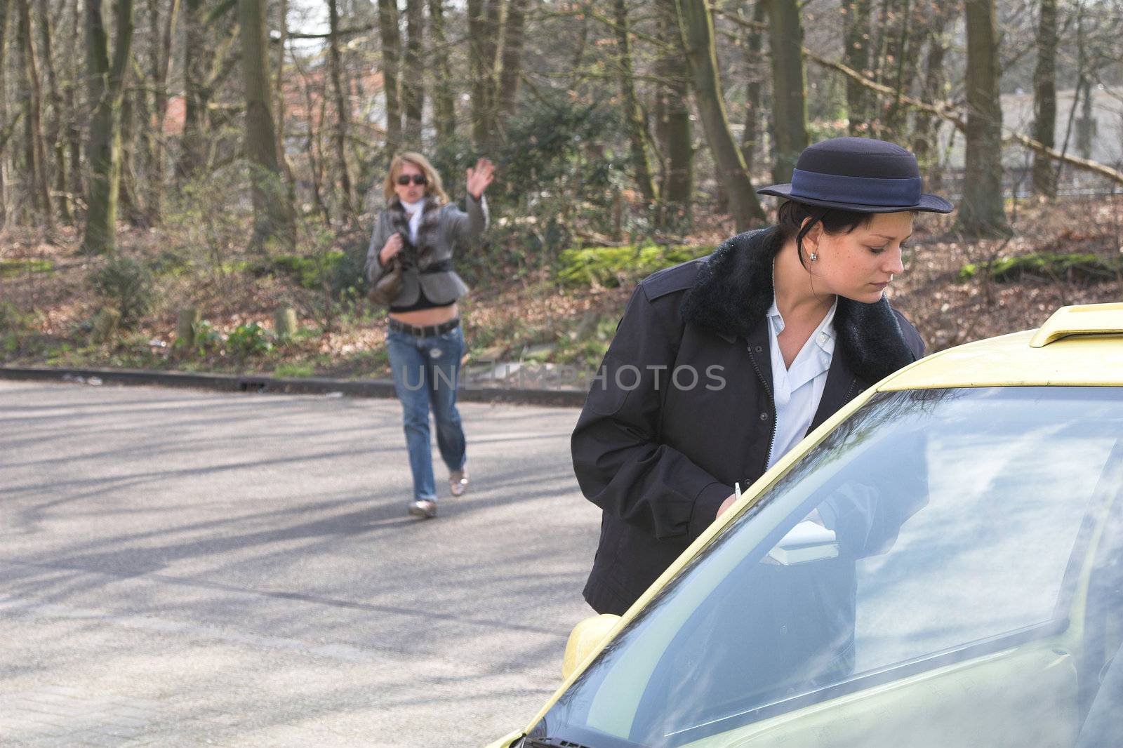 Female police officer peering inside a car to see if there is a parking ticket available. The owner of the car is running towards her