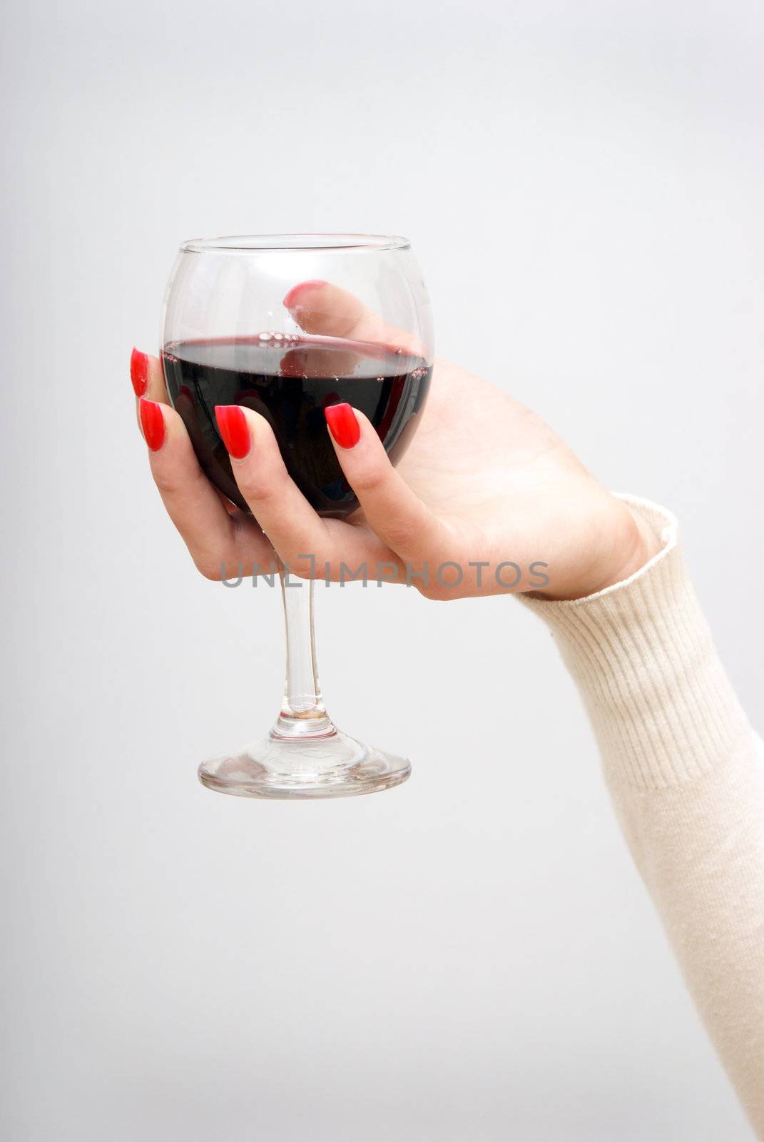 A woman holds her glass of wine up in the air.
