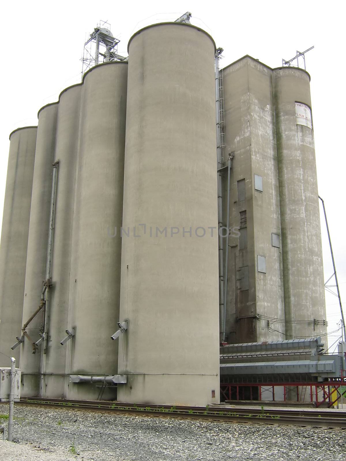 A photograph of a large grain elevator located near a railroad.