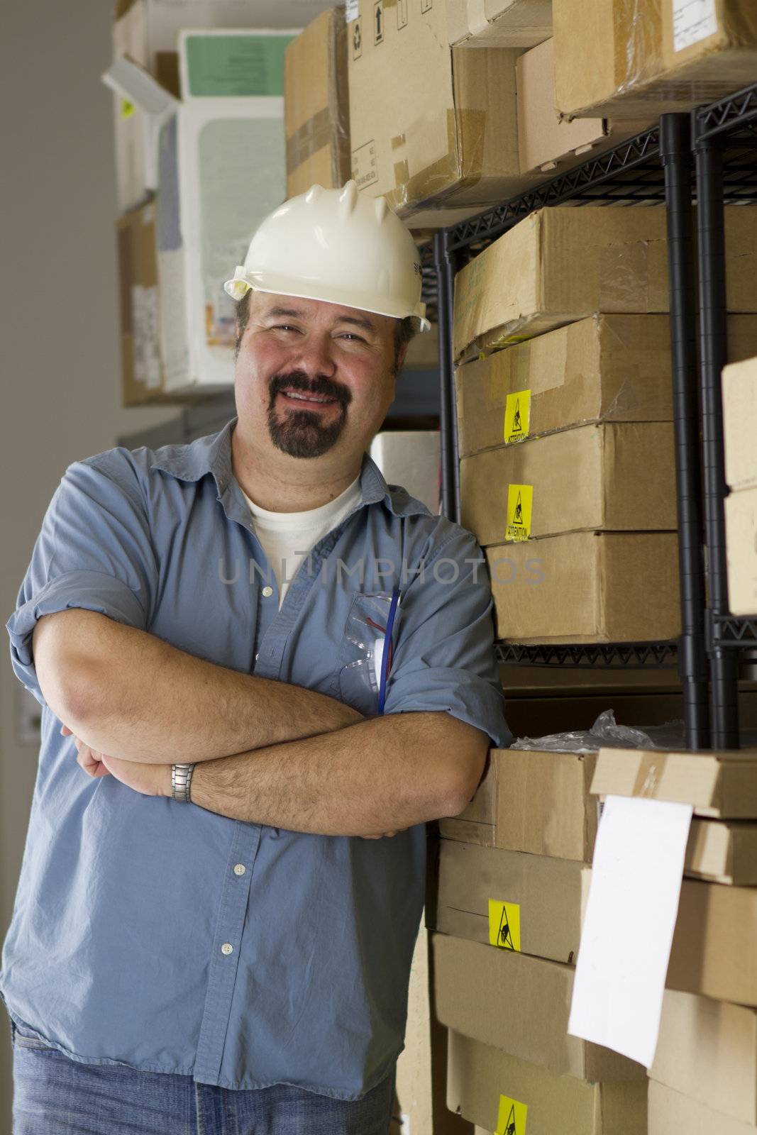 A warehouse worker posing positively to the camera by the boxes.