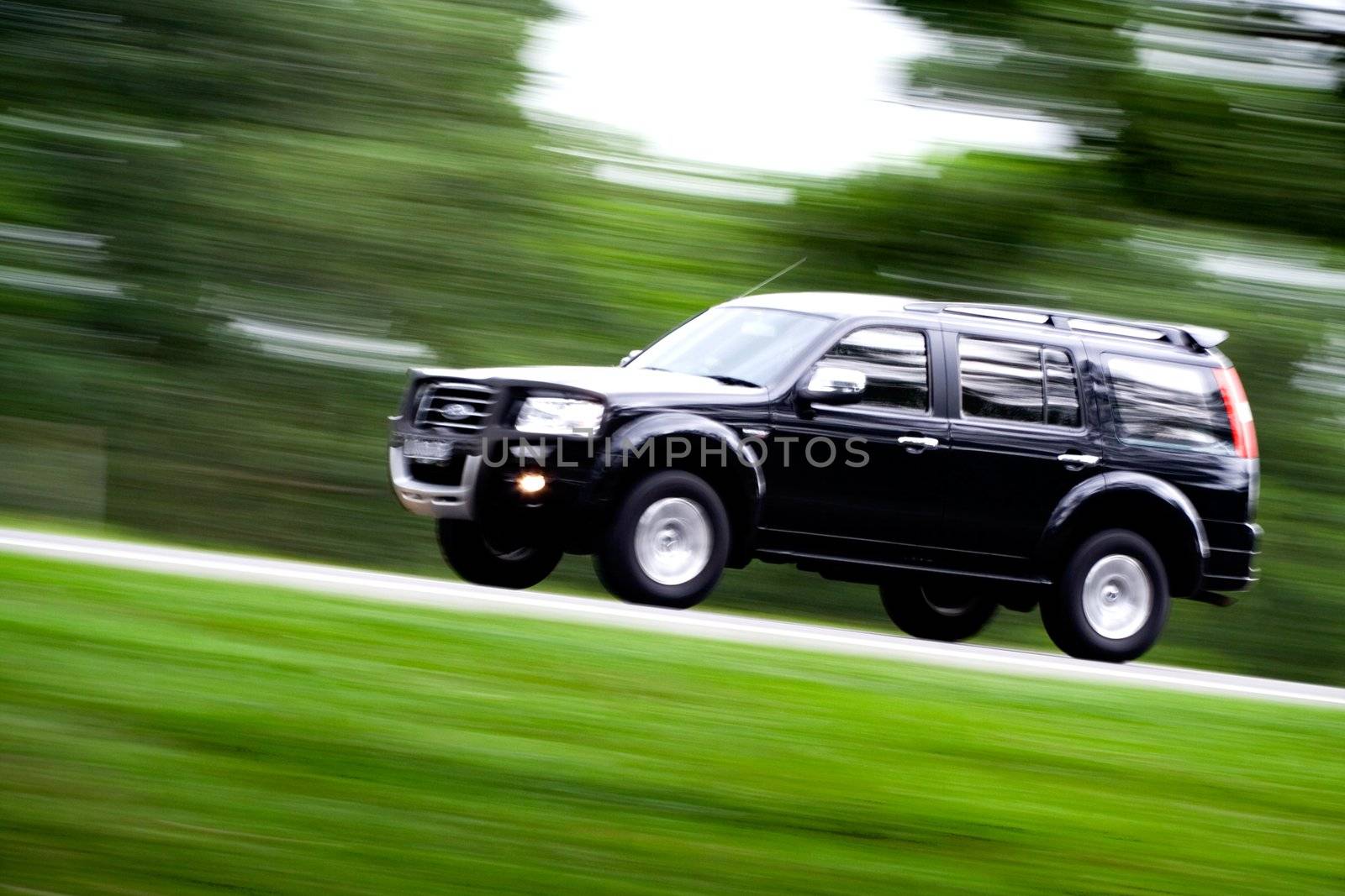 a black suv rushing away on a countryside road