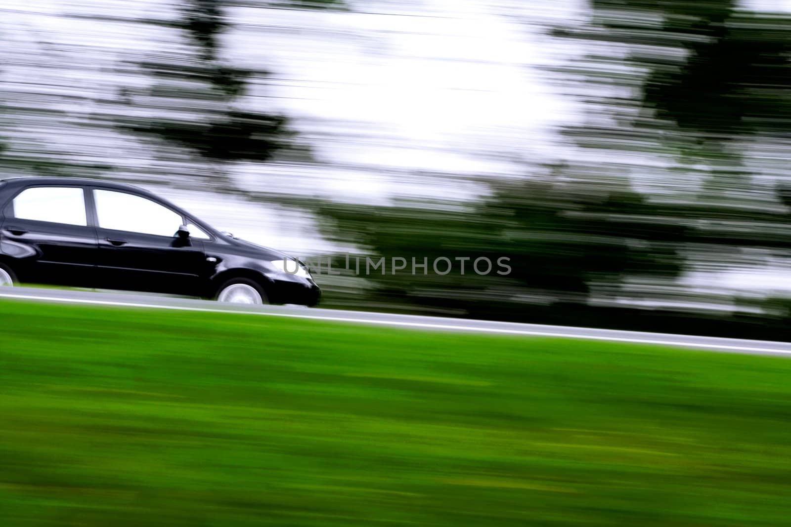 a black car rushing away on a countryside highway
