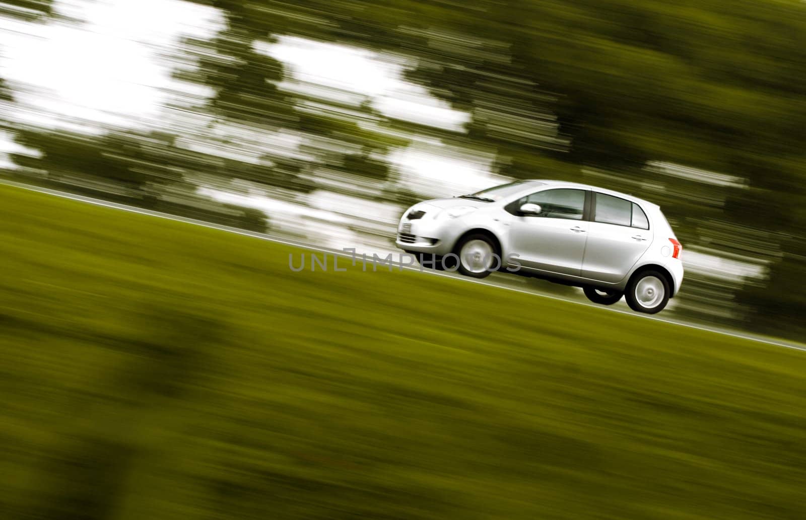 silver car rushing away on a countryside road