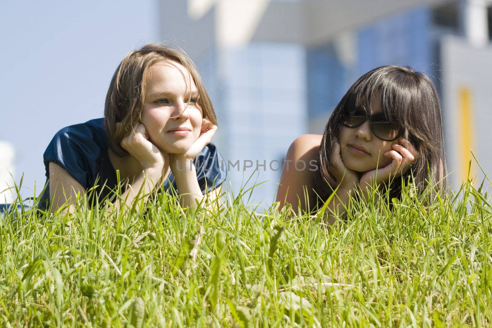 two happy smiling girls lies on a grass