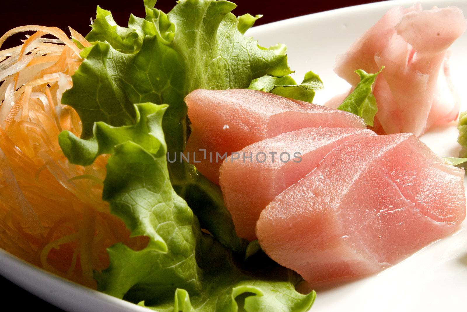 Sashimi on a platter with carrot and lettuce