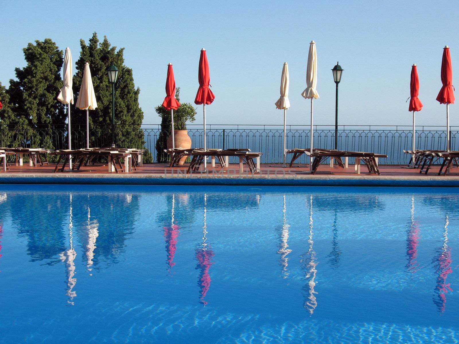 red and white umbrellas reflected in a pool