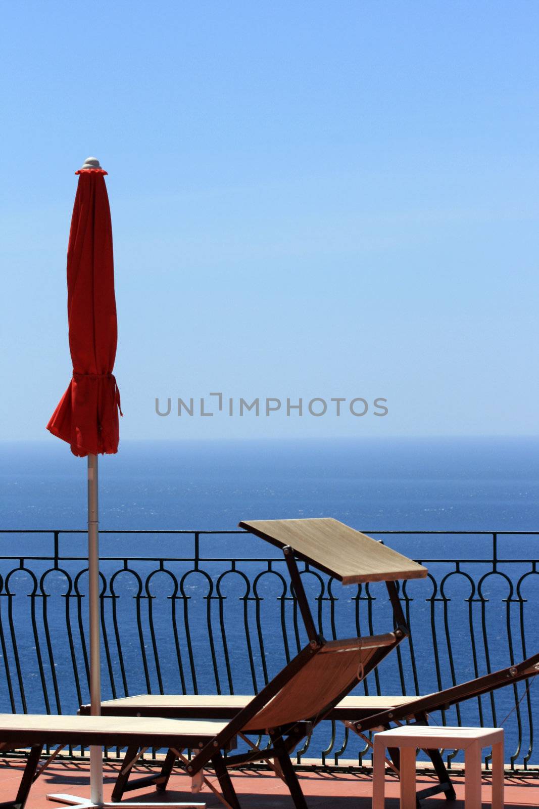 Red umbrella and sunbeds overlooking the Mediterrean Sea by keki