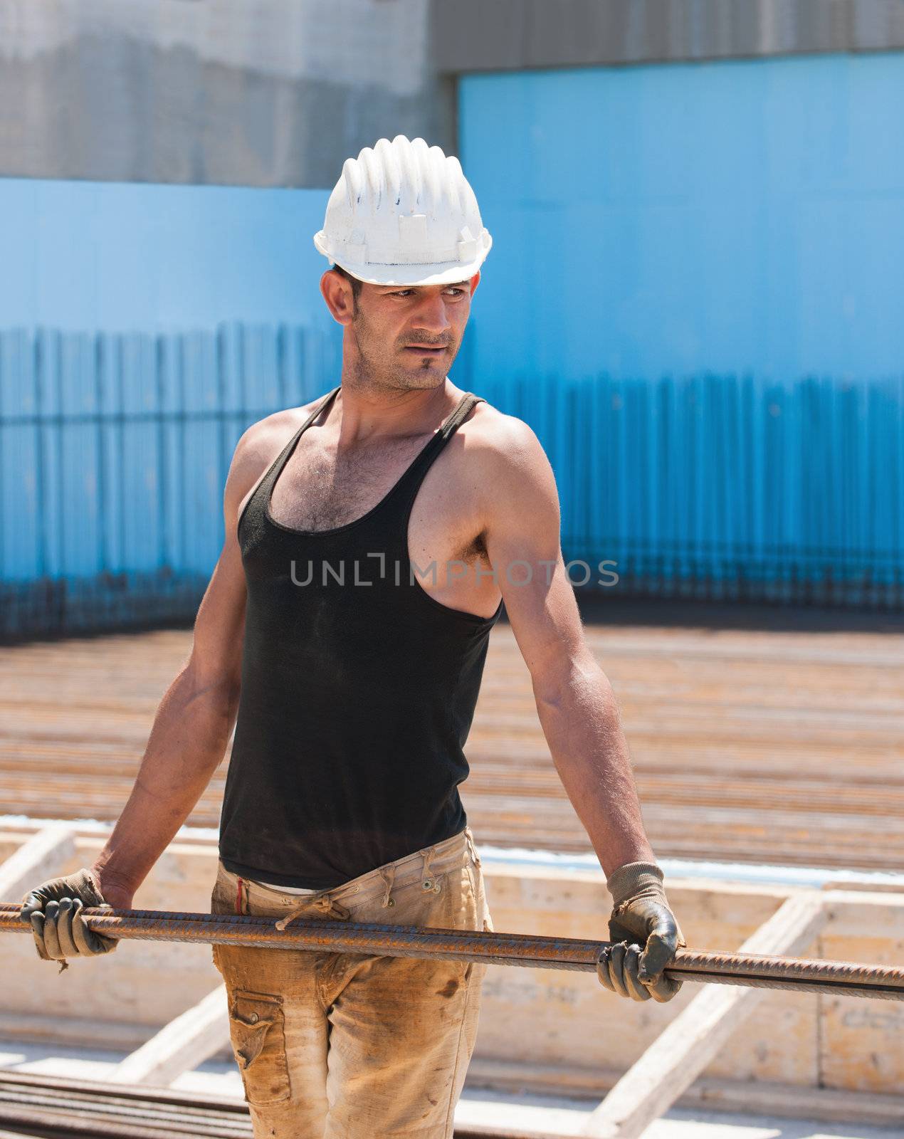 Authentic construction worker carrying reinforcement steel bars in construction site