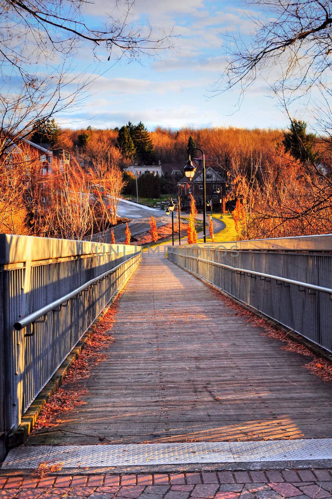 Beautiful nature scene: sun setting over the wooden bridge of a small town on a autumn day.