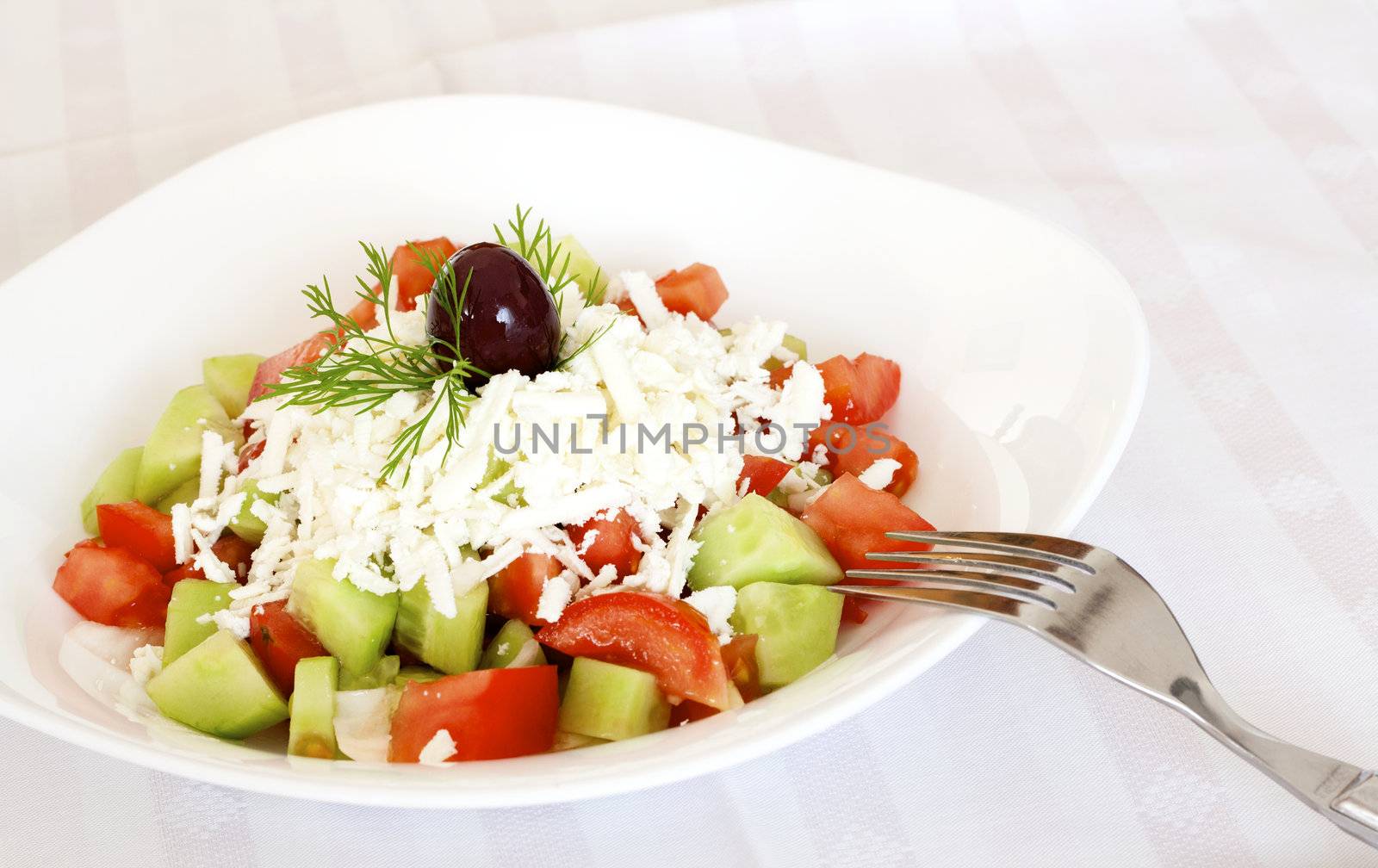 Eating fresh salad with tomatoes, cucumber, onion, feta cheese and olive.