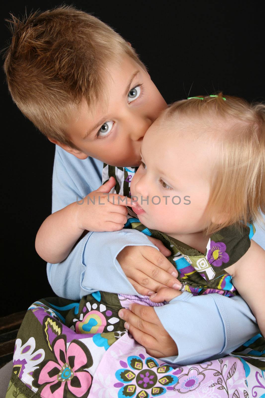 Cute brother holding his toddler sister in his arms 
