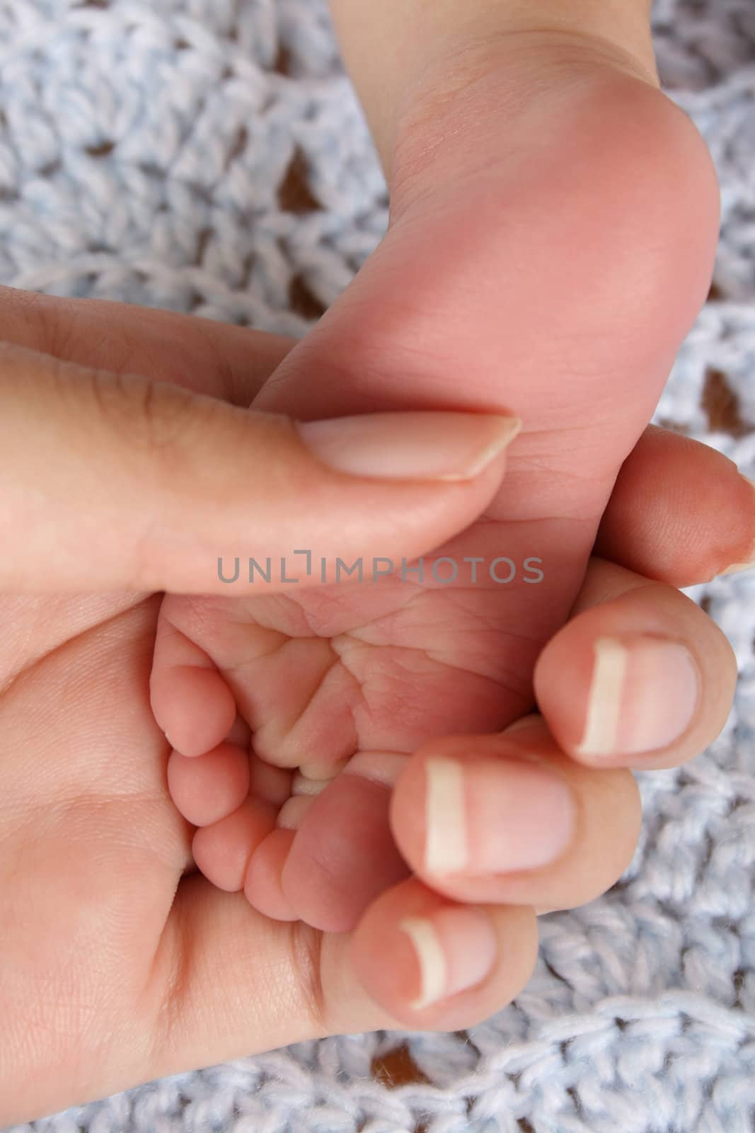 Mother holding foot of a newborn baby.  Focus on wrinkles on Foot.