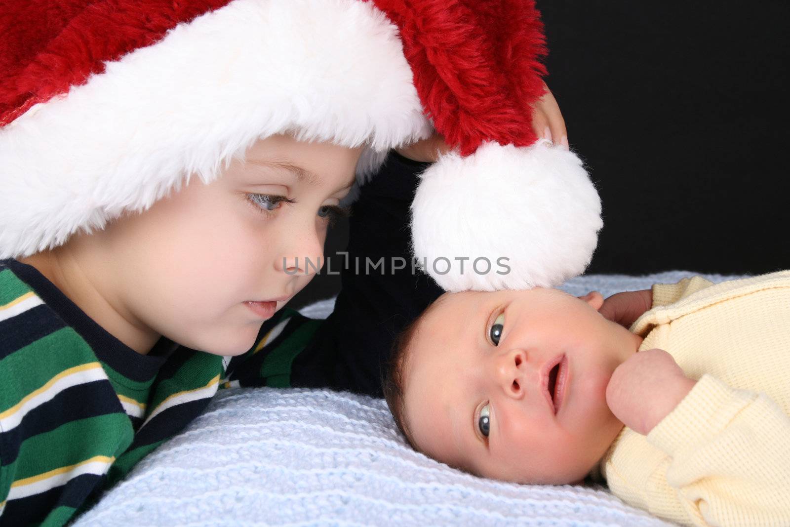 Boy wearing a christmas hat with his newborn brother