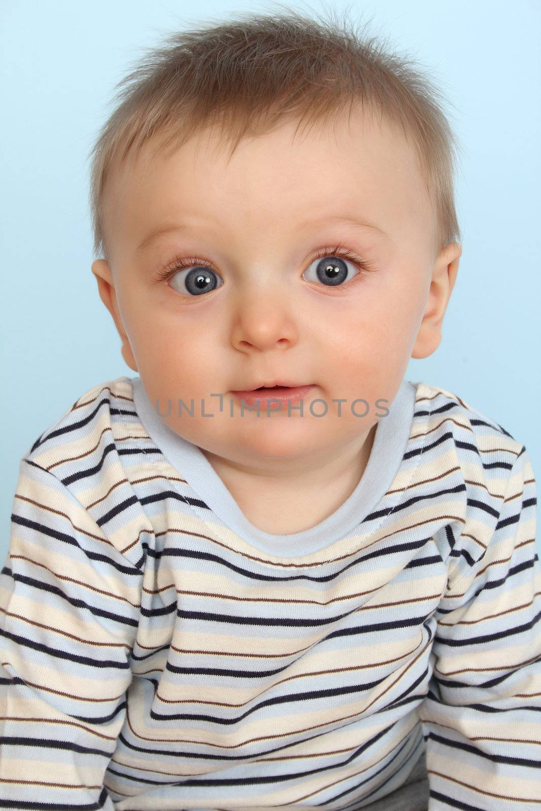 Surprized looking baby boy against a blue background