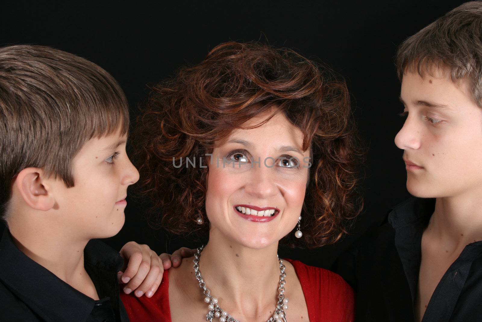 Stylish mother with her two sons on black background