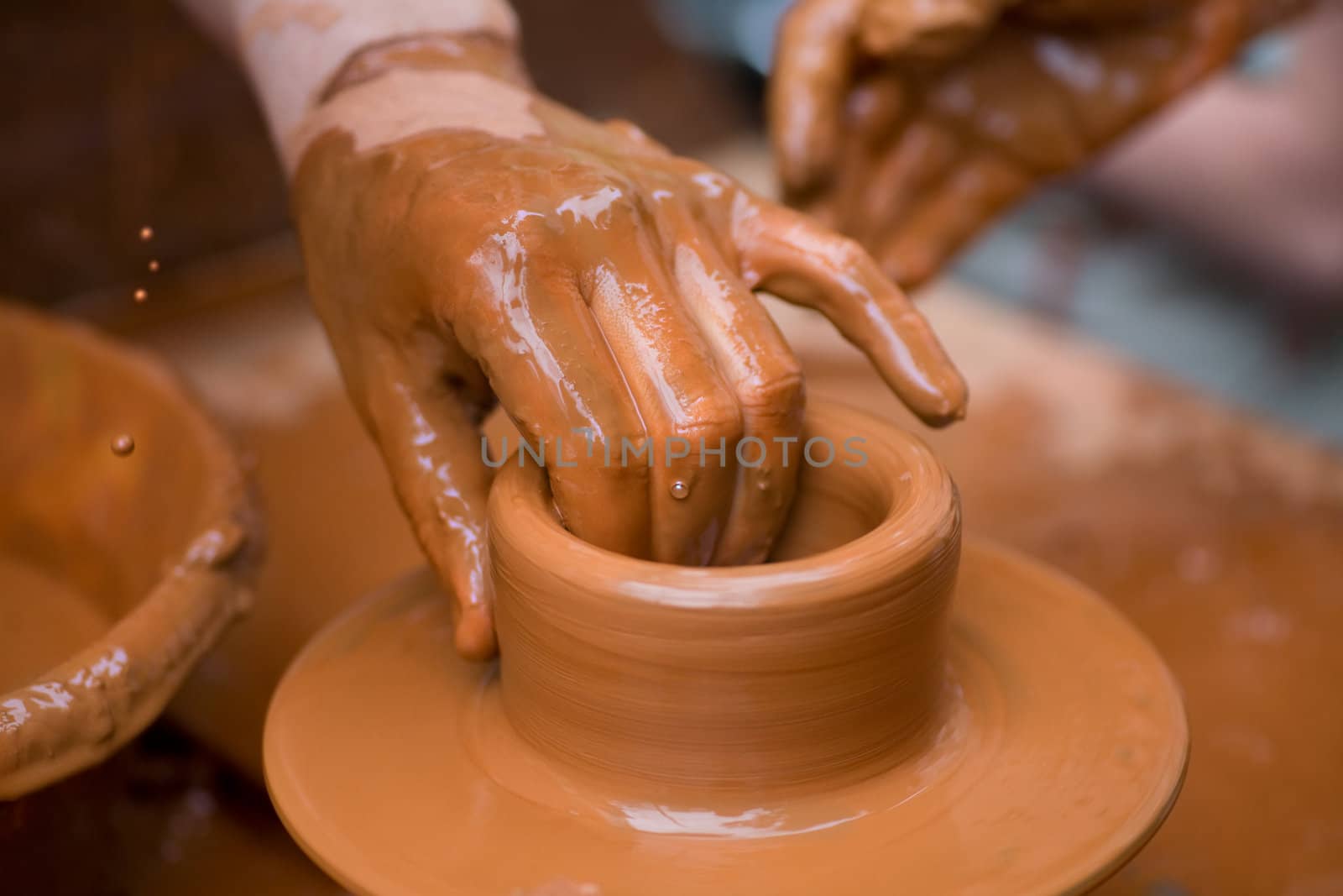 Potter shaping a ceramic plate on a pottery wheel