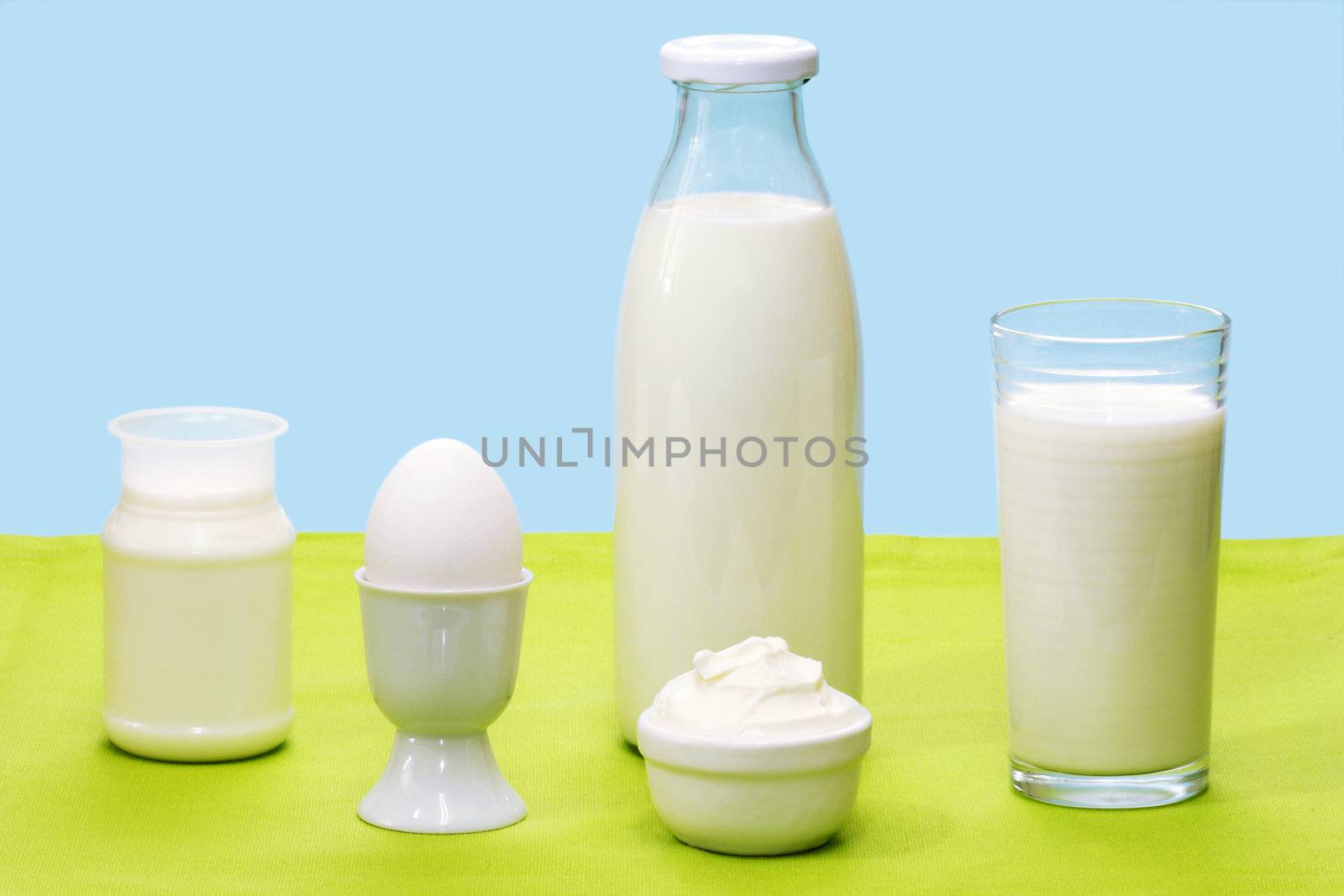 Fresh milk, yogurt, curd cheese and egg over blue background
