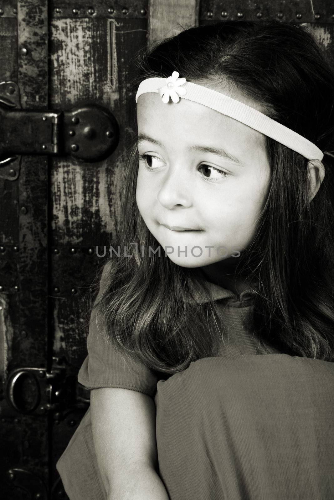 Cute brunette girl sitting against an antique trunk wearing a headband