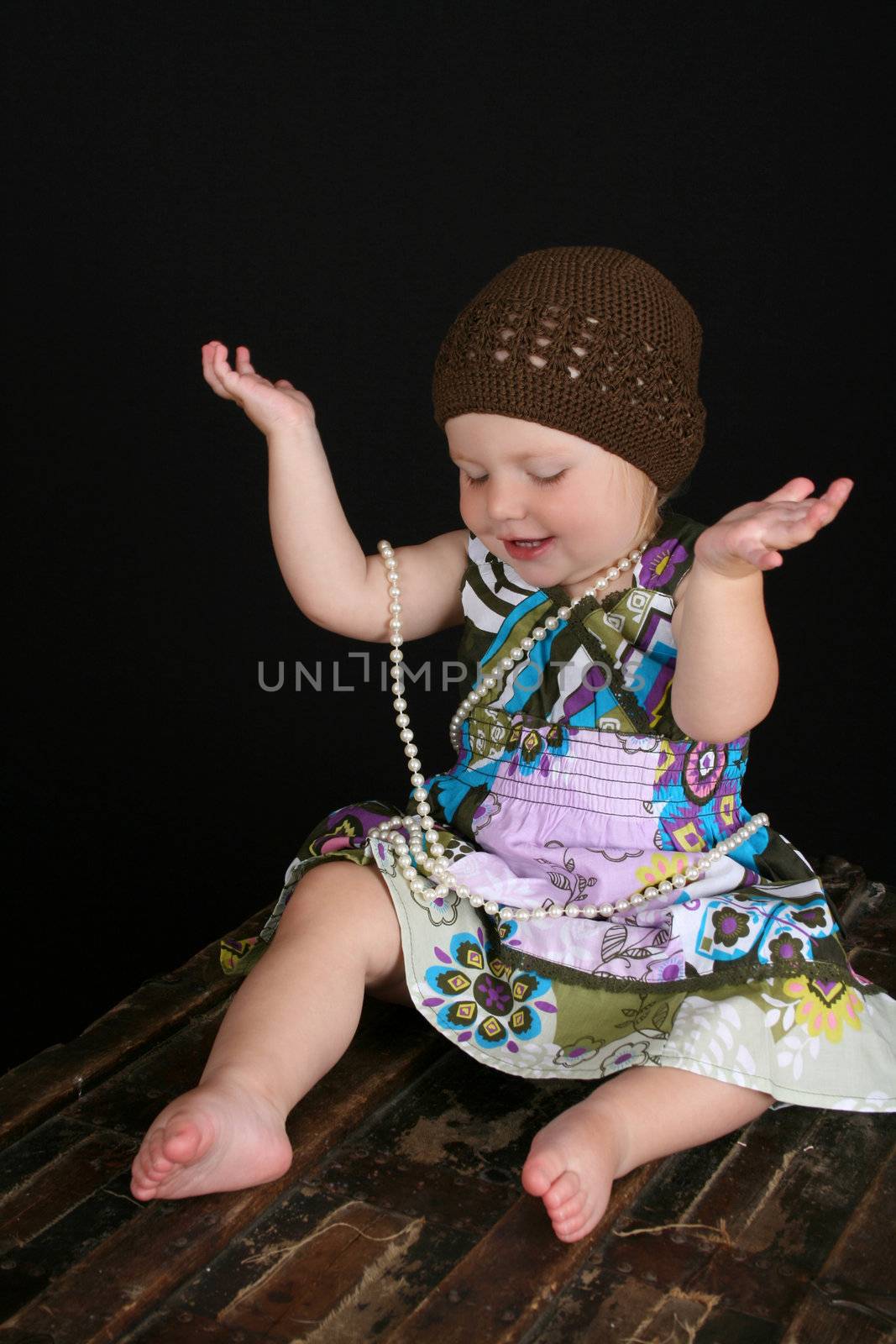 Beautiful blond toddler playing with a string of pearls