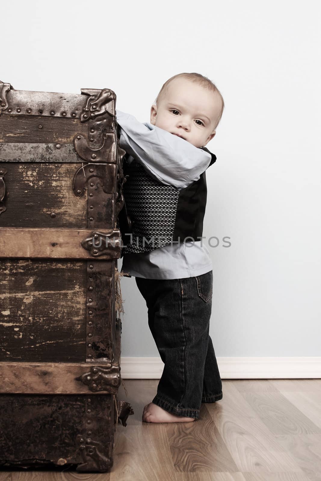 Cute baby boy standing up against an antique trunk