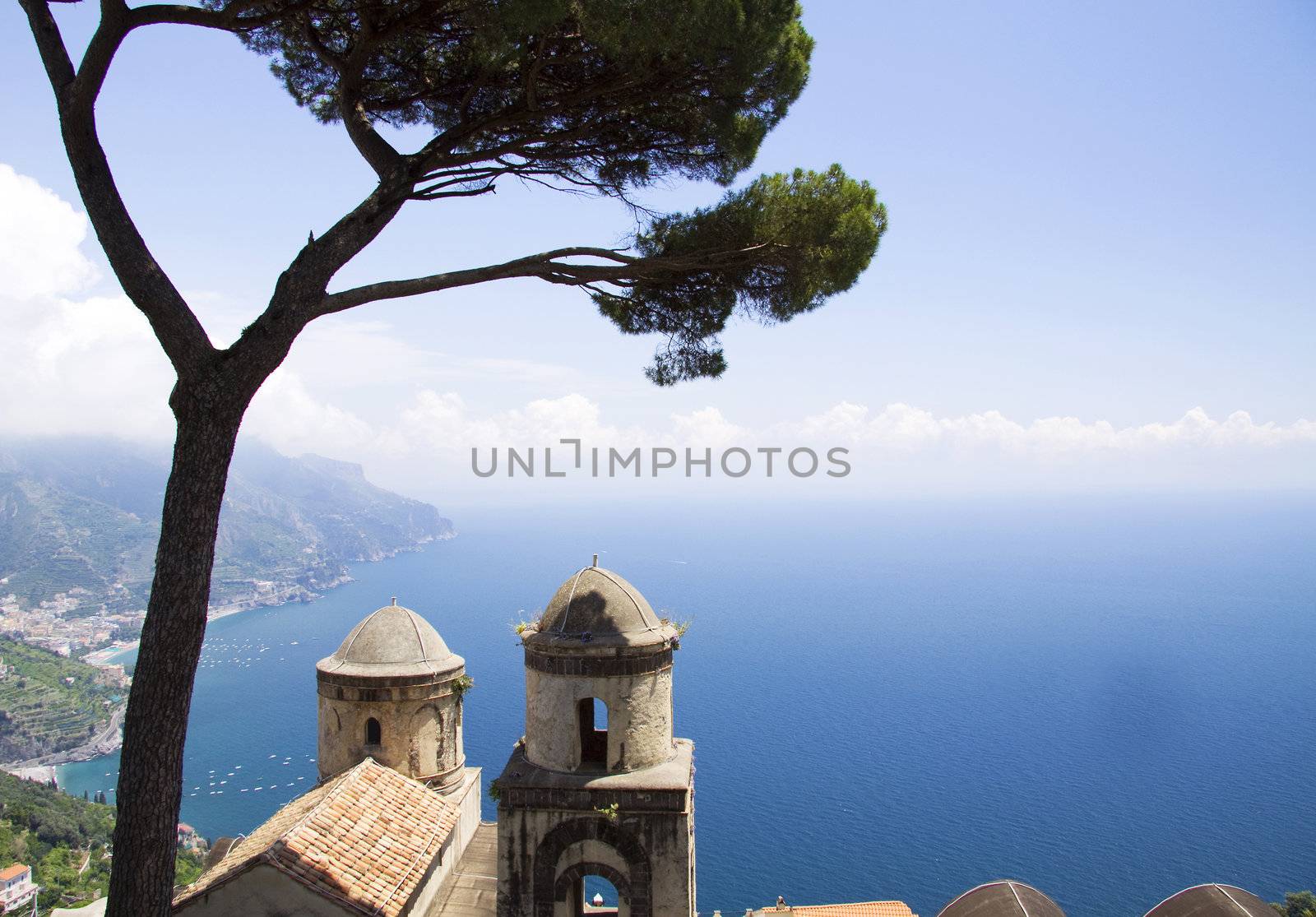 The Ravello garden offers a view of the two church towers, a tree and the Amalfi coast 