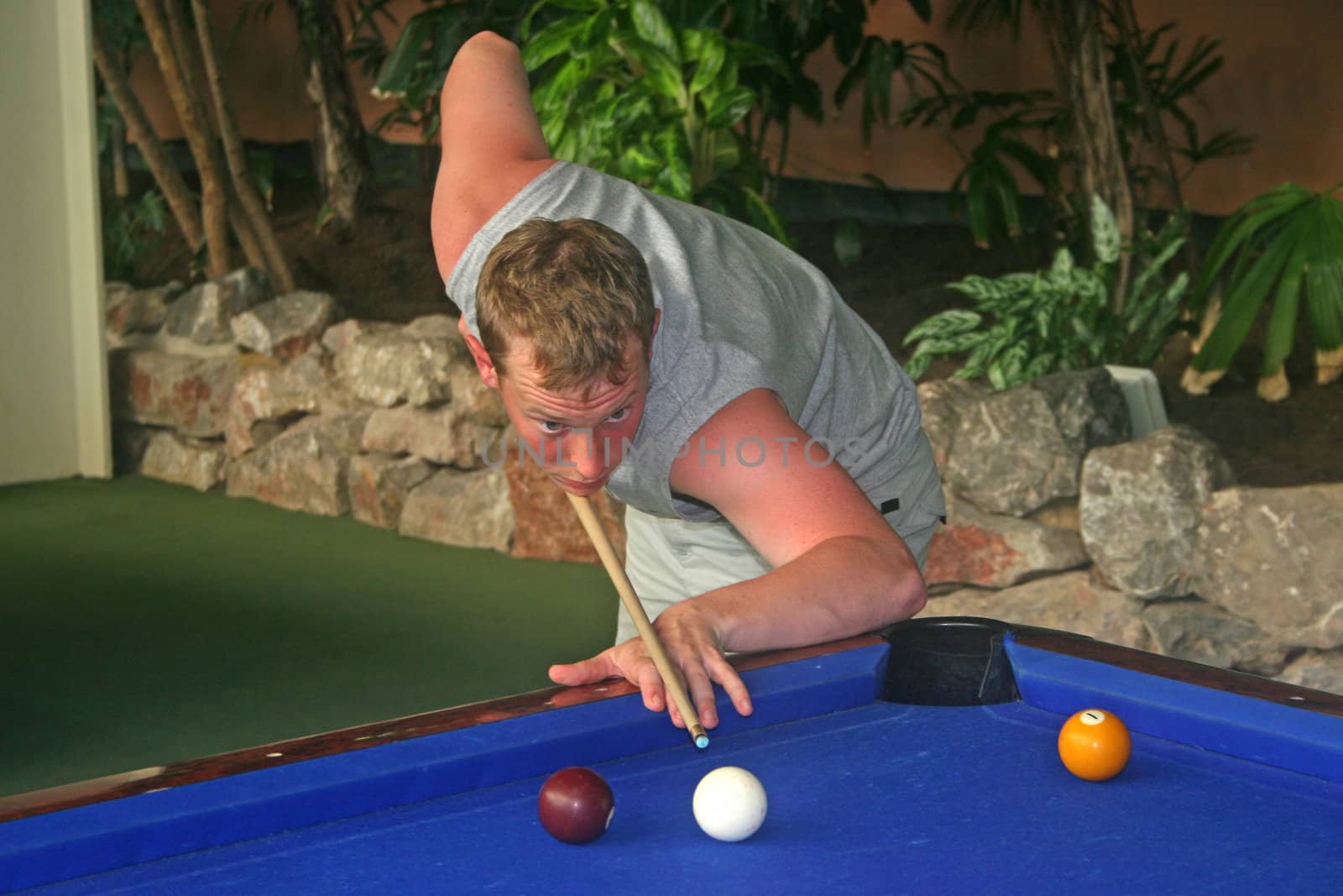 Young male playing American Pool, ready to take his shot.