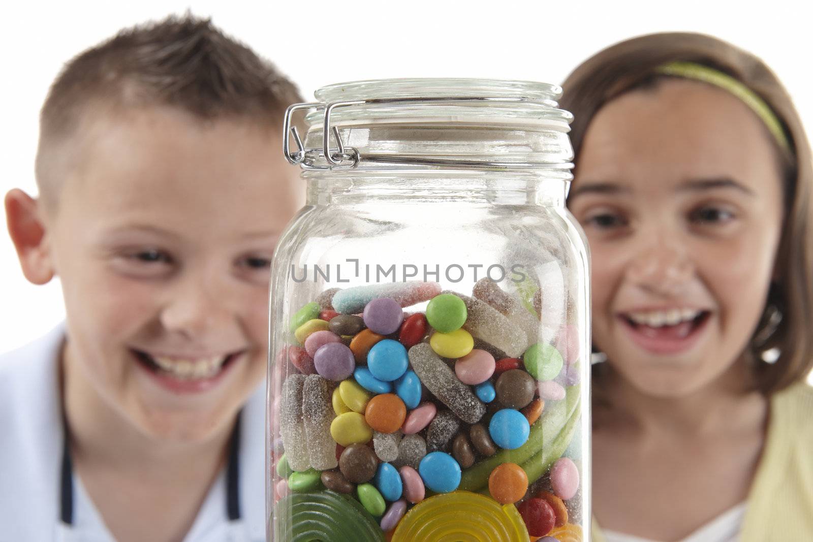 young girl and boy looking with excitement at candy jar