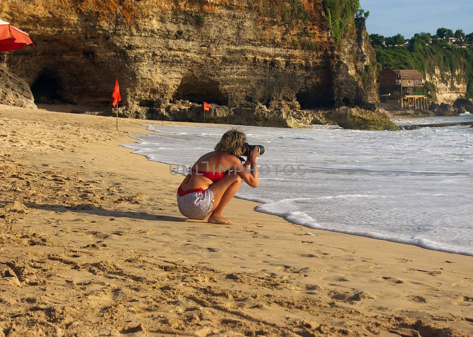 Female photoghrapher, photographing on Dreamland beach, Bali, Indonesia.