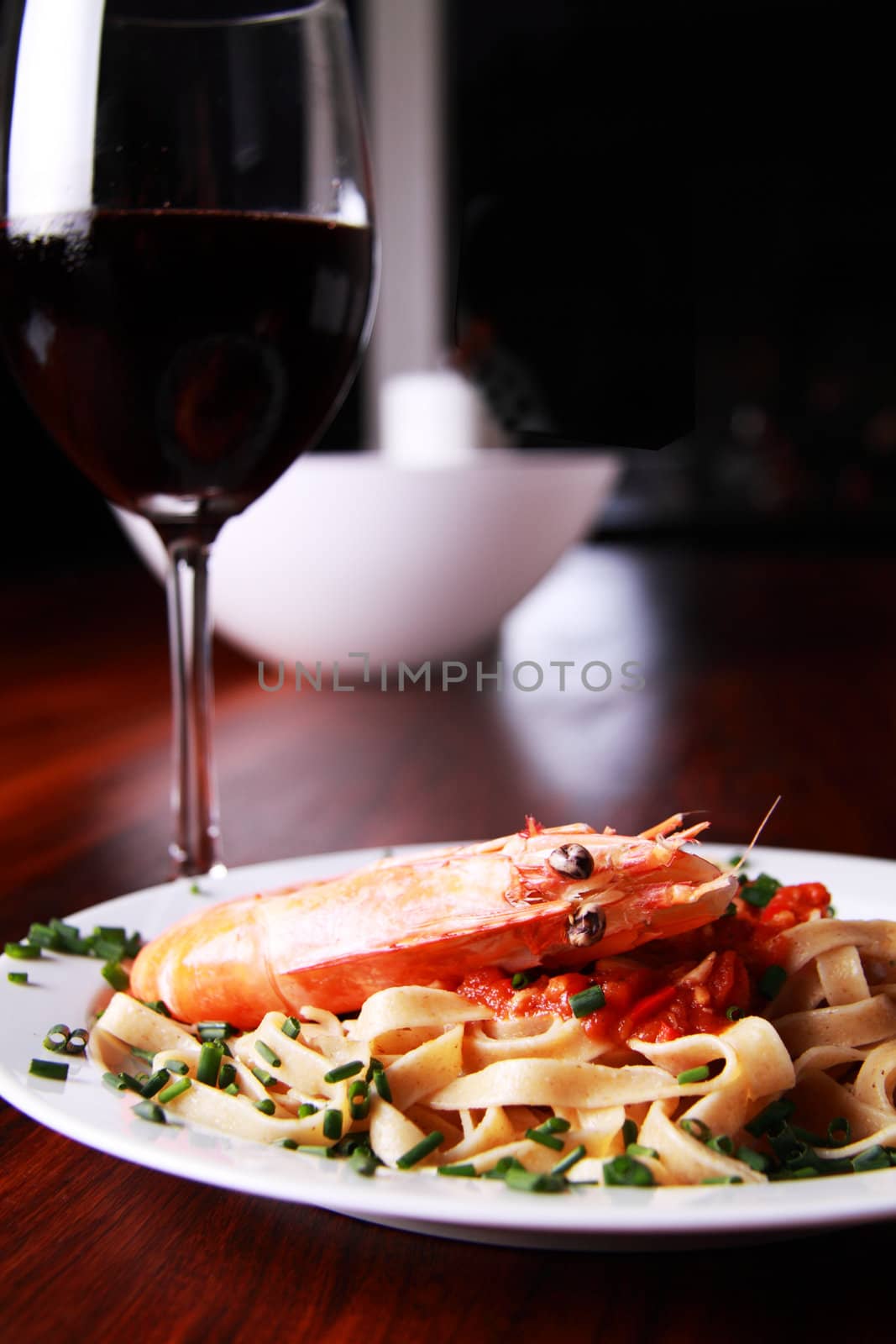 Shrimp pasta on a white plate served on a mahoney table