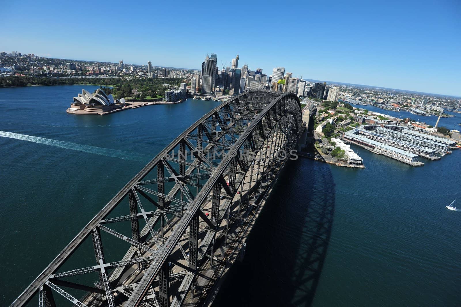 An aerial view of the Sydney Harbour Bridge as the sunlight shimmers on the water below.