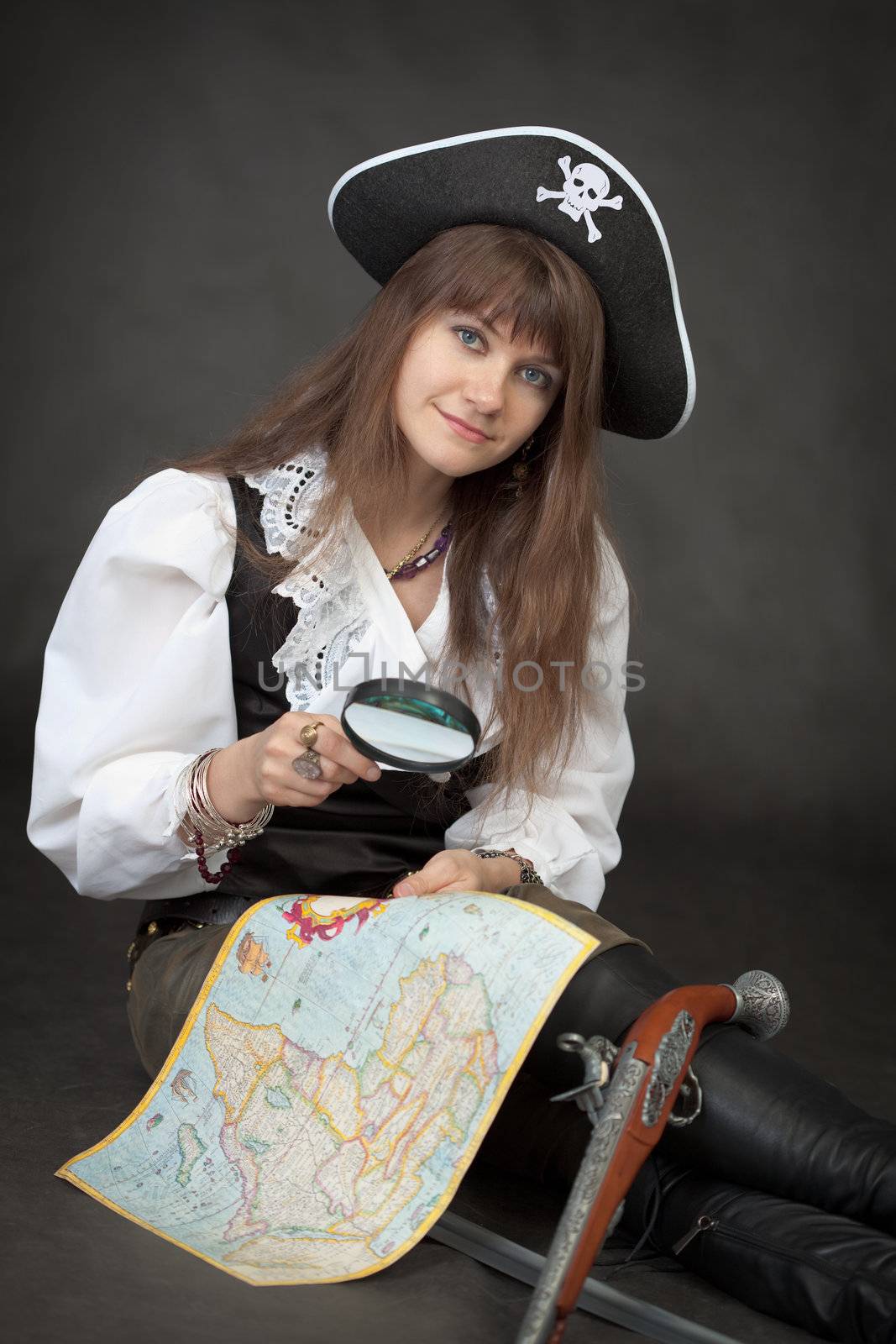 Pirate girl with sea map and pistol sit on a black background