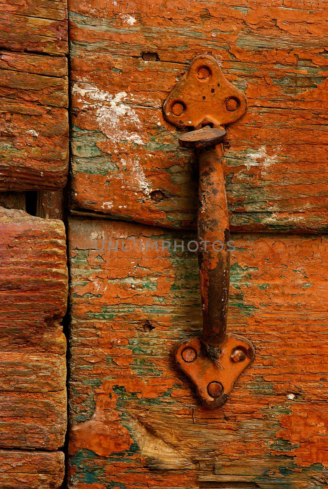 Image shows a rusty handle on a highly textured country door