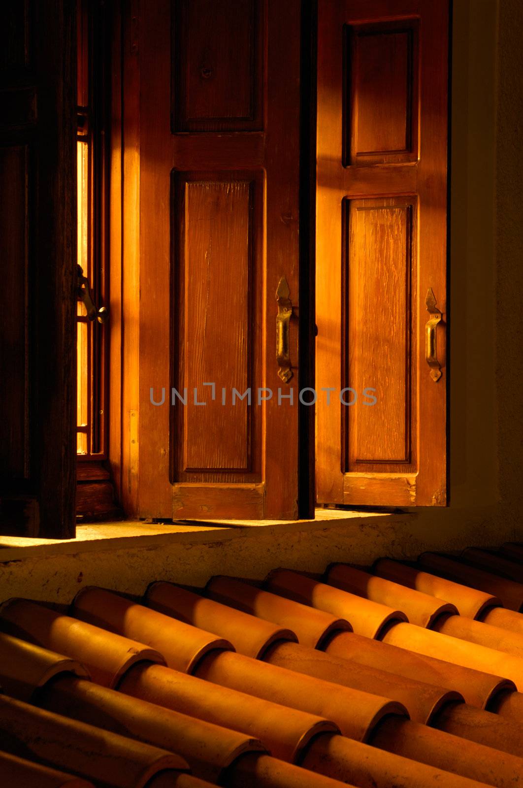 Picture shows an open window allowing golden light to illuminate the roof outside 