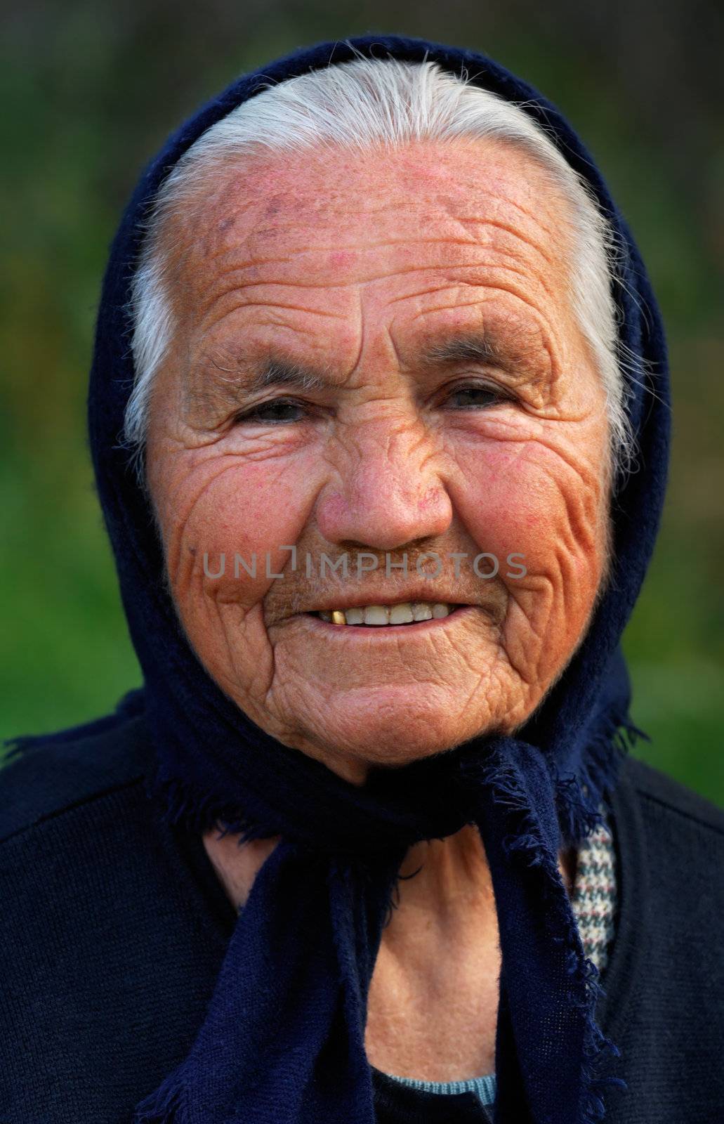 Image shows a portrait of an old Greek happy lady, wearing a scarf