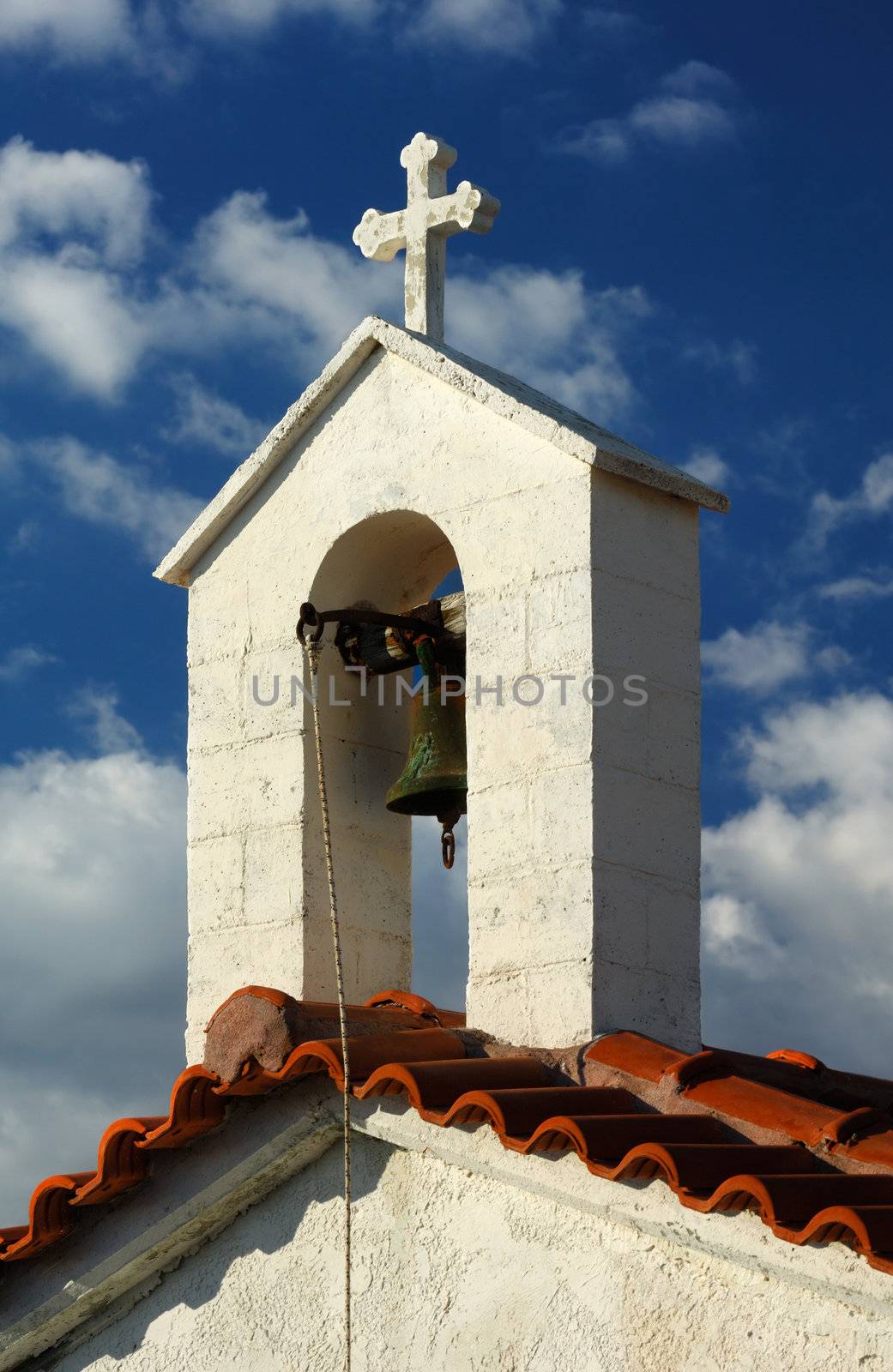 A Greek countryside chapel against a blue cloudy sky