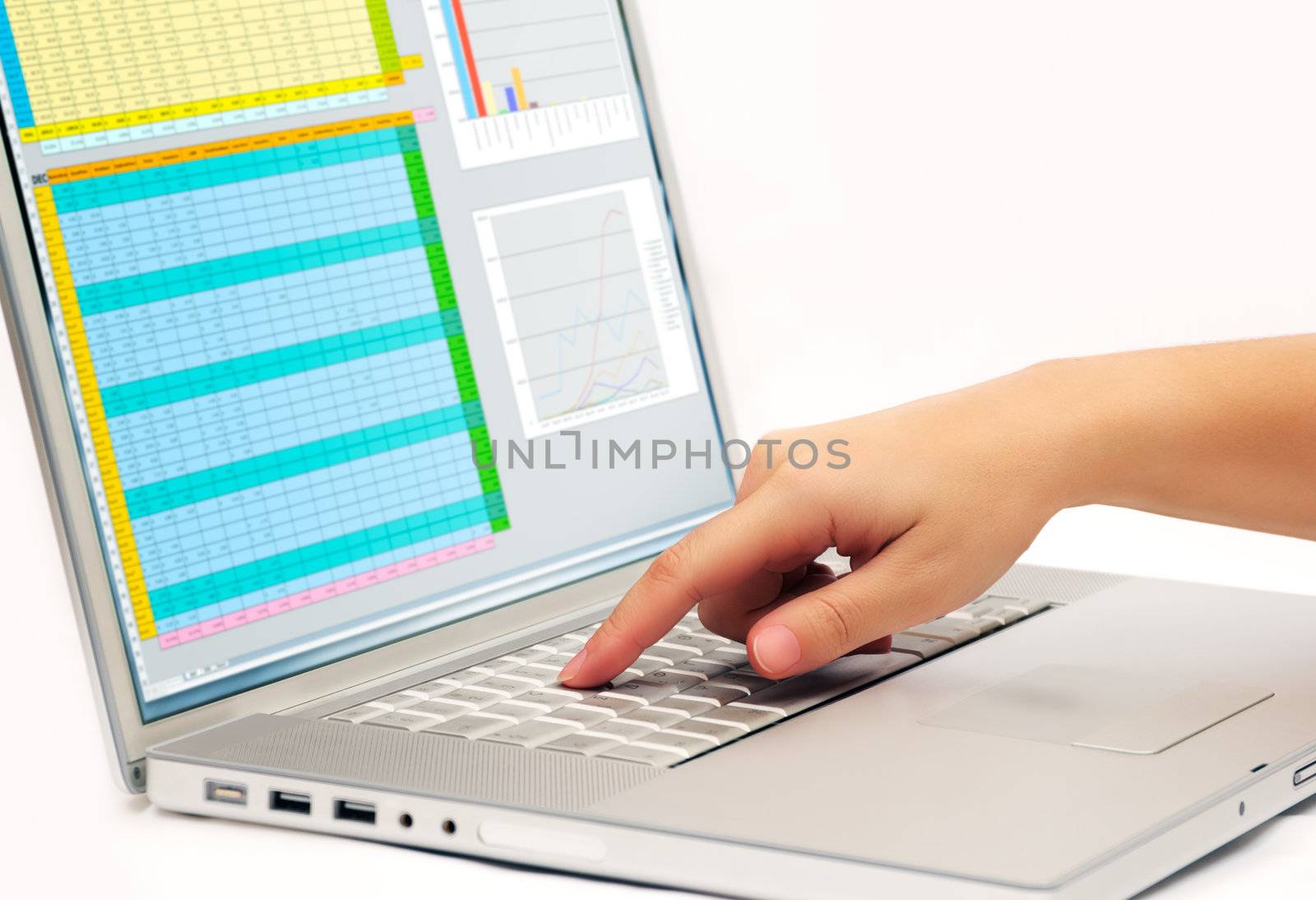 Image shows a finger pressing a key on a contemporary laptop  displaying a business spreadsheet