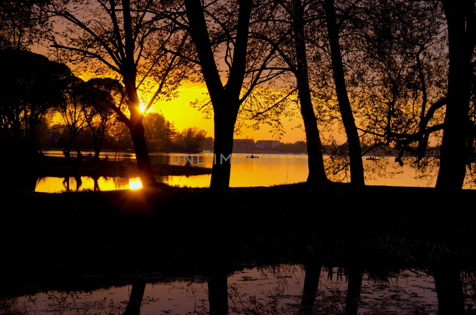 Romantic amazing colorful sunset reflects on river in early spring. Fishermen in the beautiful nature painting.