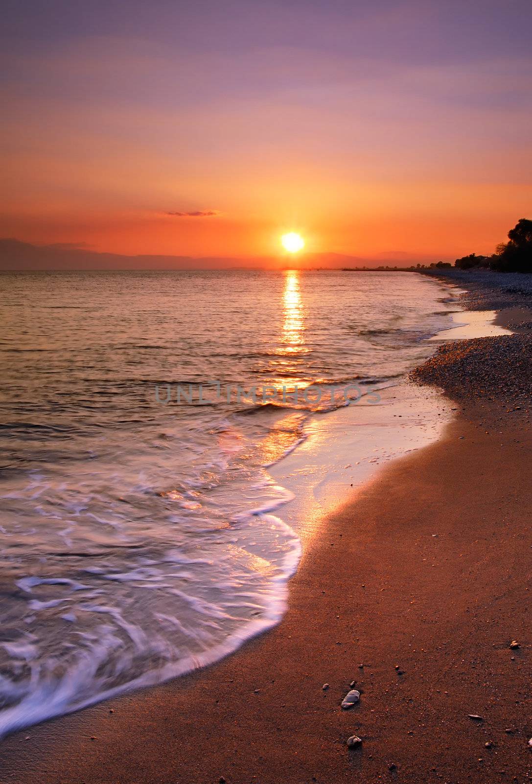 image shows a deserted beach at sunset
