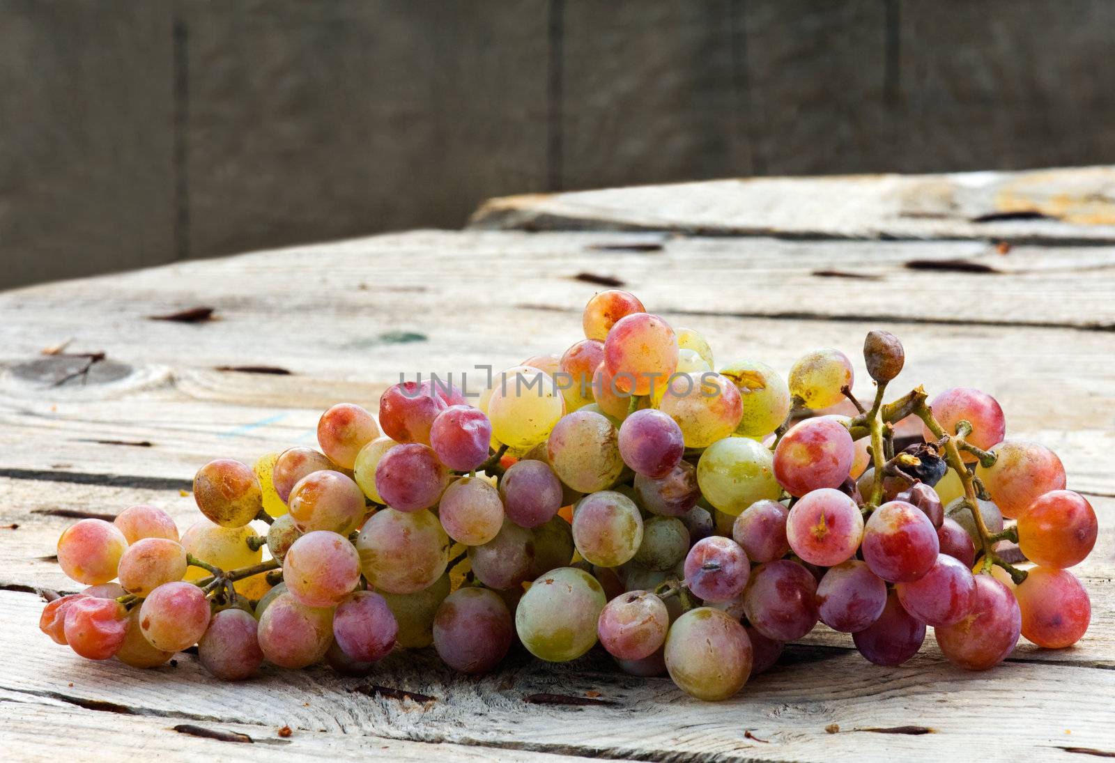 Image shows a bunch of grapes on a wooden table