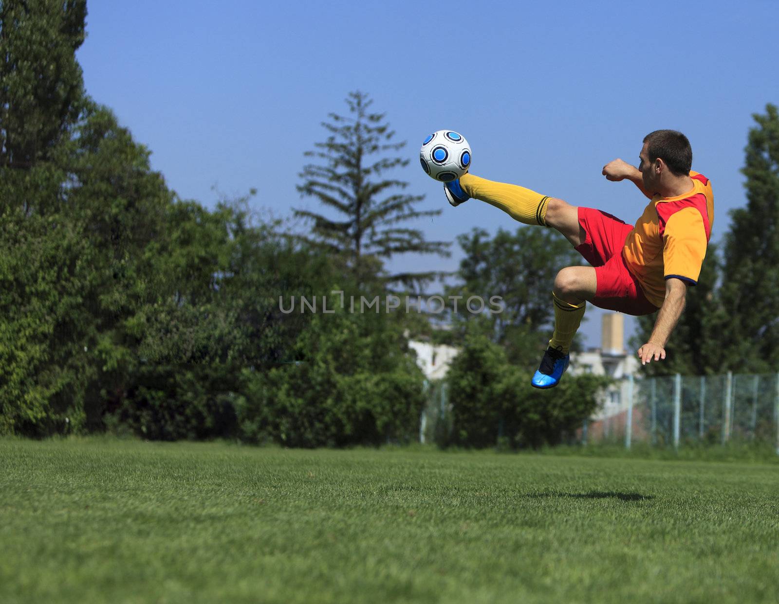 A soccer player kicking the ball in an acrobatic position.